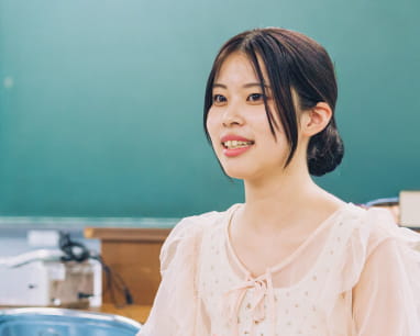 教室の机に座り、笑顔で話をしている女性の姿