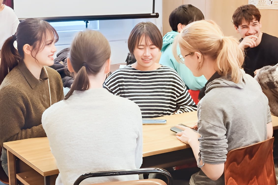 教室内で複数の学生がグループに分かれて話し合いや作業をしている様子