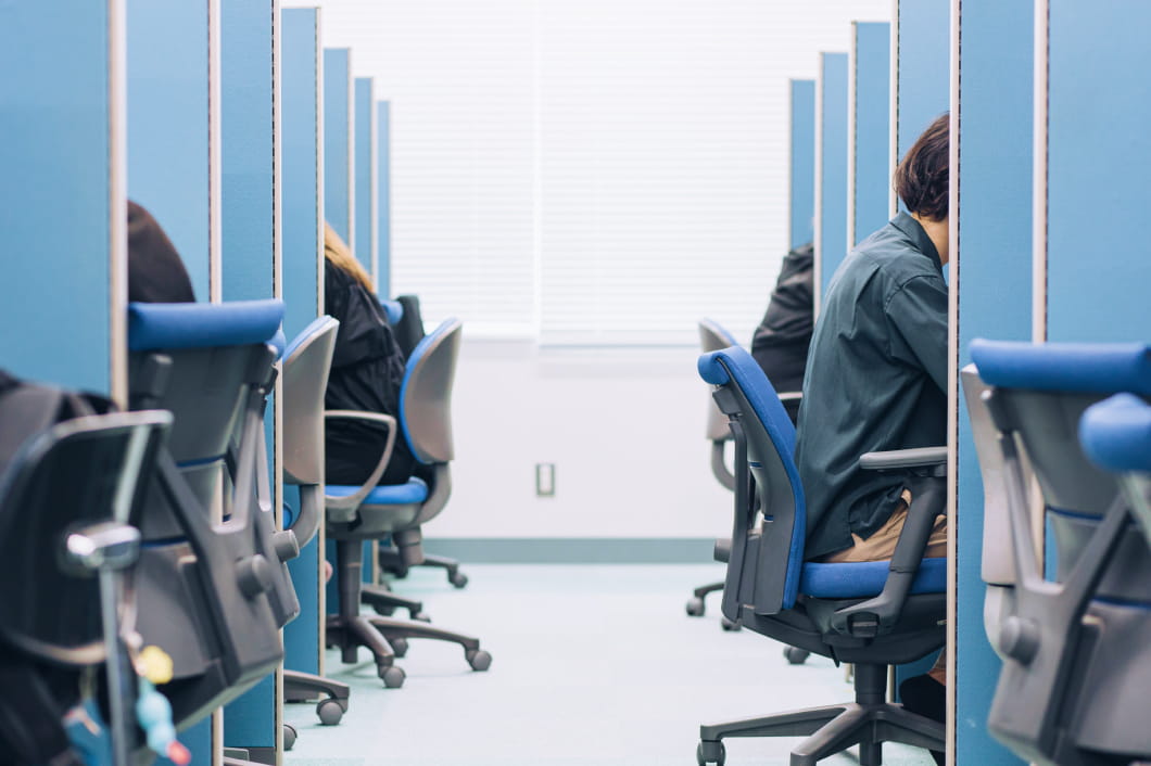 パーティションで仕切られた自習ブースに複数の学生が座り、静かに勉強している様子