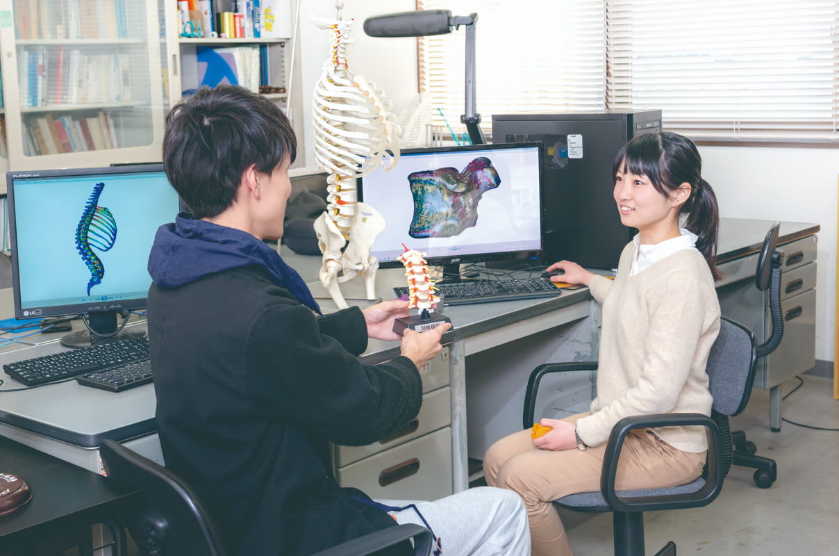 骨格模型や背骨のミニチュア、人体の3D画像を用いて、学習をしている学生たちの様子