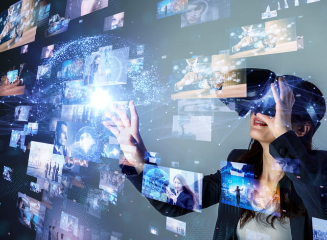 VRゴーグルを装着した女性が、仮想空間内の映像や情報に手を伸ばして操作している様子