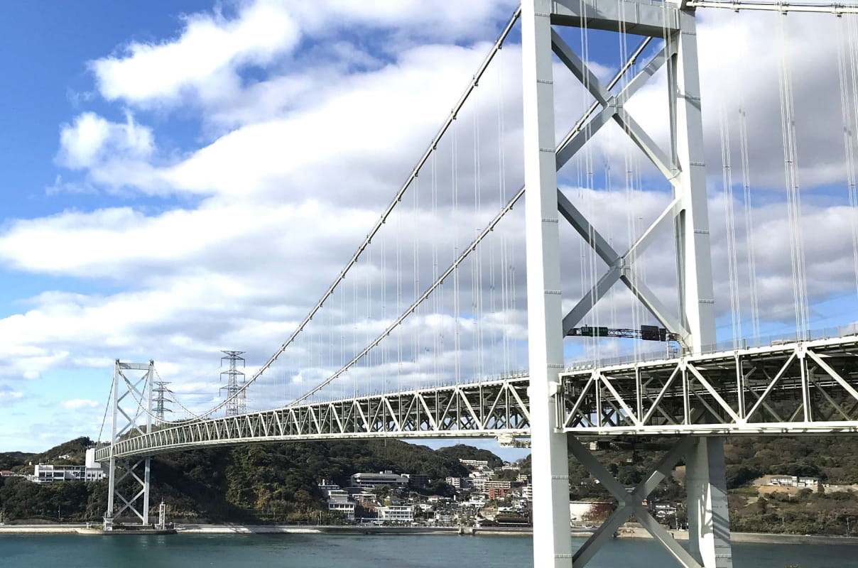 大型吊り橋が海をまたいで架けられている風景で、土木インフラの象徴的な構造物